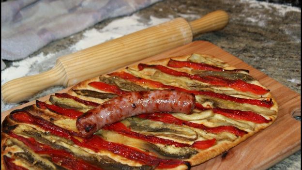 Pizza vegetal acompañada por una salchicha de la zona