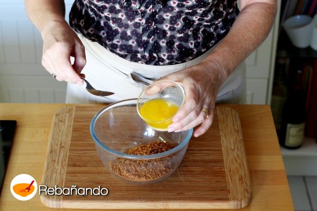 Verter las galletas molidas en un bowl y agregar la manteca derretida